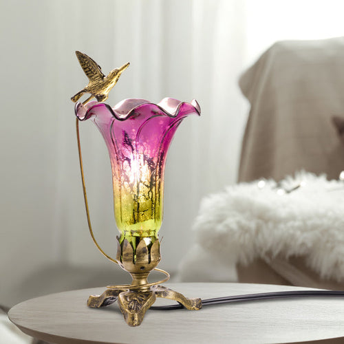 10.25"H Hand Blown Mercury Glass Hummingbird Lily Lamp on an end table.