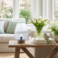 L10.5" H Briggs Blue/White Ombre Globe-Like Shade Accent Lamp with a Mango Wood Block Base in a living room with a wooden coffee table featuring a vase of white tulips and books.