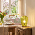 10.5" H Lila Chartreuse Green Glass Shade with a Mango Wood Block Base Accent Lamp in a dining room with a wooden table, and floral arrangements.