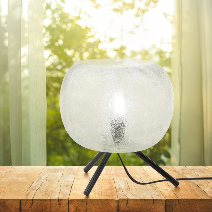 11.5" H Libby Black Tripod Table Lamp with a Textured Clear Glass Globe Shade on a wooden surface with a blurred green outdoor background