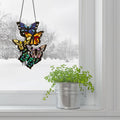 13.25" H Butterfly Cluster Stained Glass Window Panel hanging on a snowy window with a plant below
