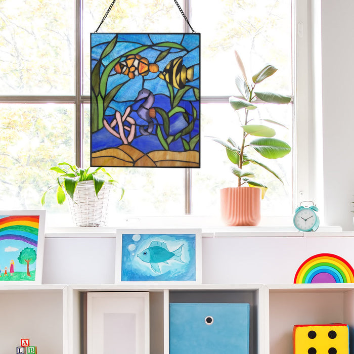 14" H Underwater Ocean Scene Stained Glass Window Panel hanging in window with plants on a shelf with other colorful art pieces.