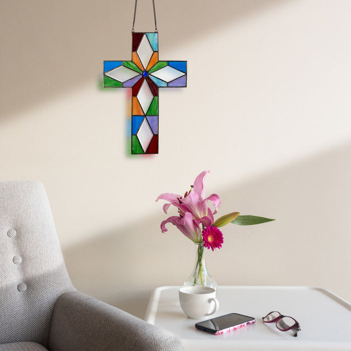 15" H Tiffany-Style Cross Stained Glass Window Panel on a wall above a table with a cup, phone, and glasses.
