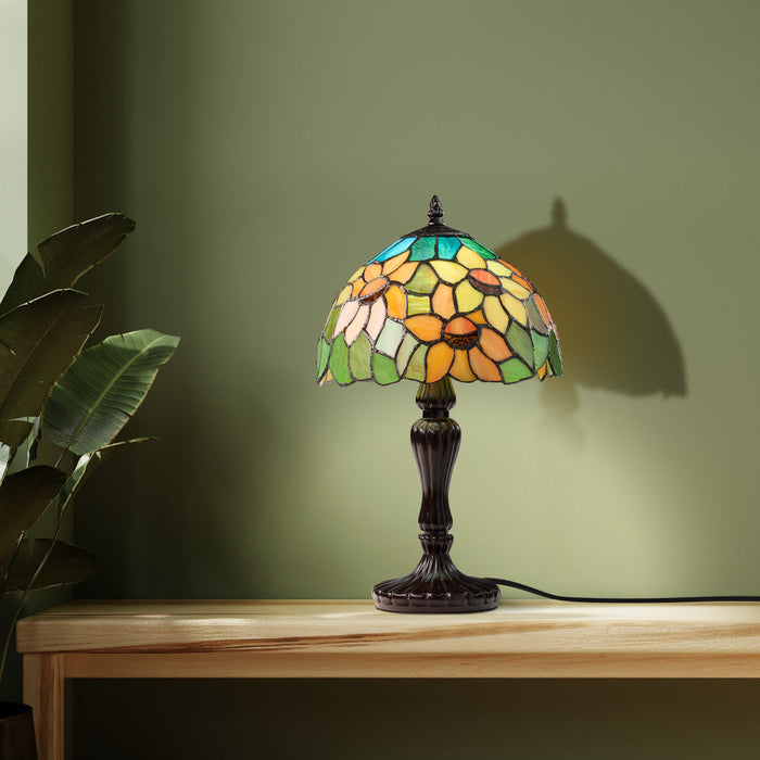 16.5" H Sunflowers Stained Glass Candlestick Table Lamp on a wooden surface against a green wall.