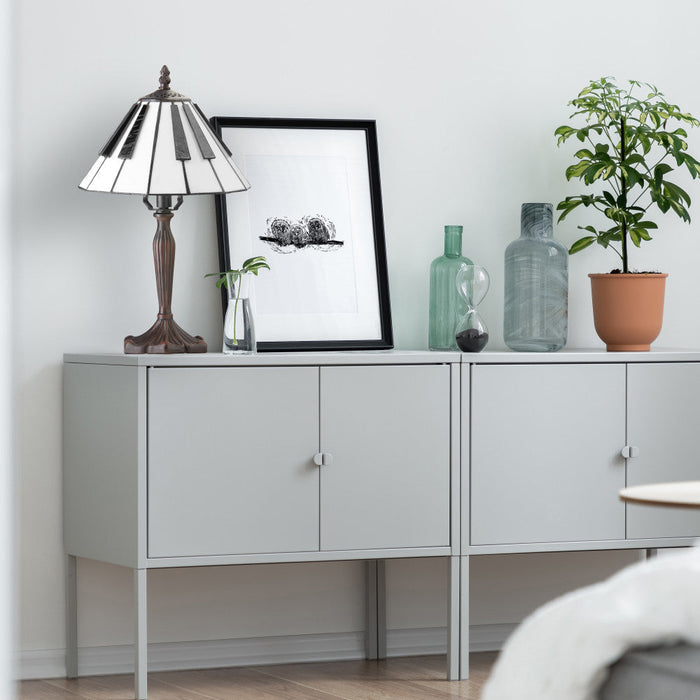 16"H Black and White Stained Glass Piano Keys Table Lamp on a light gray sideboard with decorative items including plants and bottles against a white wall.