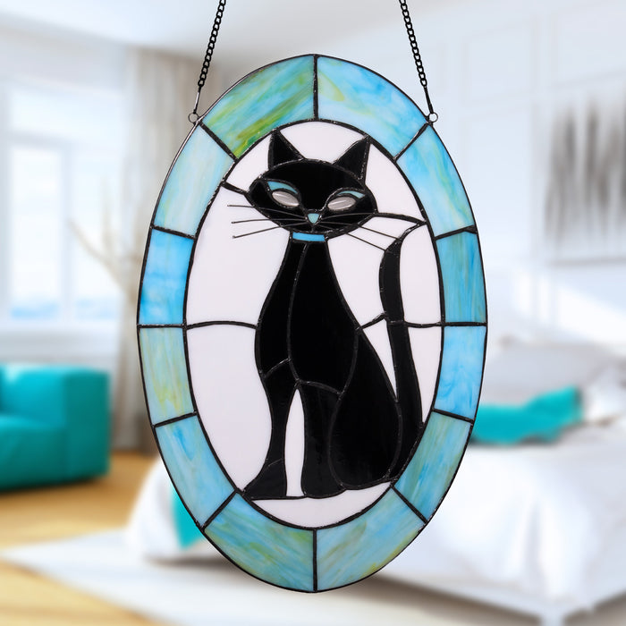 17" H Tiffany-Style Halloween Cat Stained Glass Window Panel hangs from a black chain in a brightly lit, modern bedroom.