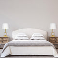 17.75"H Marler Gold & White Twin Table Lamps next to a neatly made bed with white bedding and gray blanket in a bedroom setting.