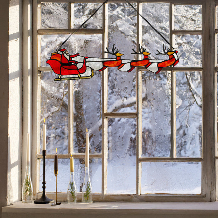 18" W Santa's Sleigh Tiffany-Style Stained Glass Window Panel hanging in front of a snowy window view.