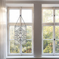 20" H Clear Floral Beveled Glass Window Panel hanging in front of a window with a view of trees.