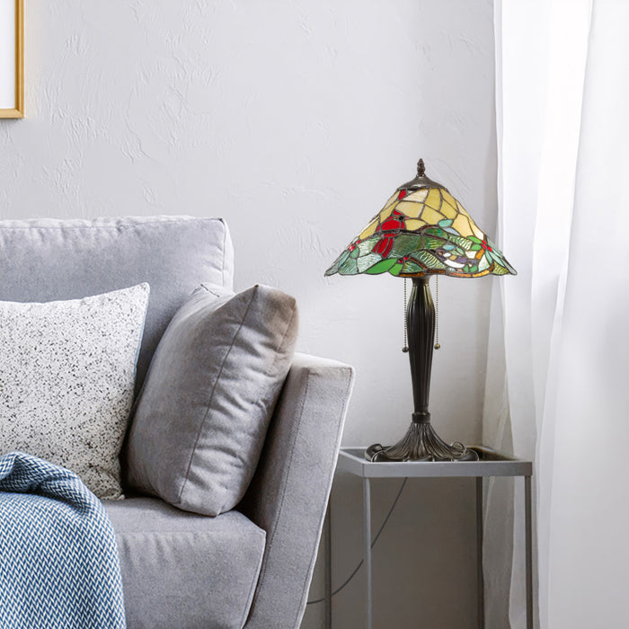 21.5" H Crimson Cardinal Tiffany-Style Stained Glass Cone Shade Candlestick Table Lamp displayed on a gray side table next to a gray sofa in a living room setting.