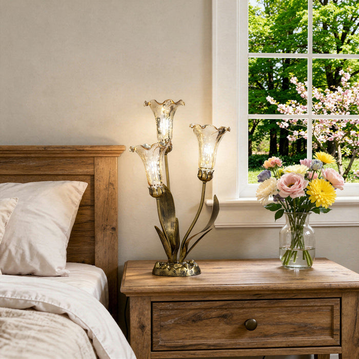 21.75"H Hand Blown Mercury Glass 3 Lily Uplight Accent Lamp on a wooden nightstand with a vase of flowers next to a bed.