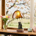 21.75"H Intellectual Monkey Table Lamp on a wooden surface near a window with cherry blossoms.
