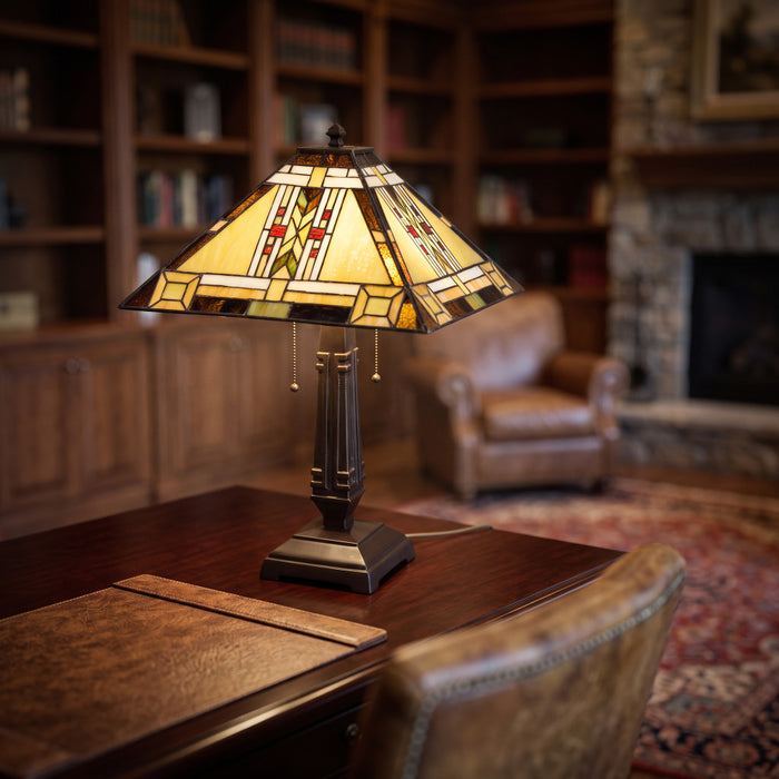 24" H Winslow Tiffany-Style Stained Glass Empire Shade Candlestick Table Lamp, placed on a wooden desk in a cozy, softly blurred study or living room.