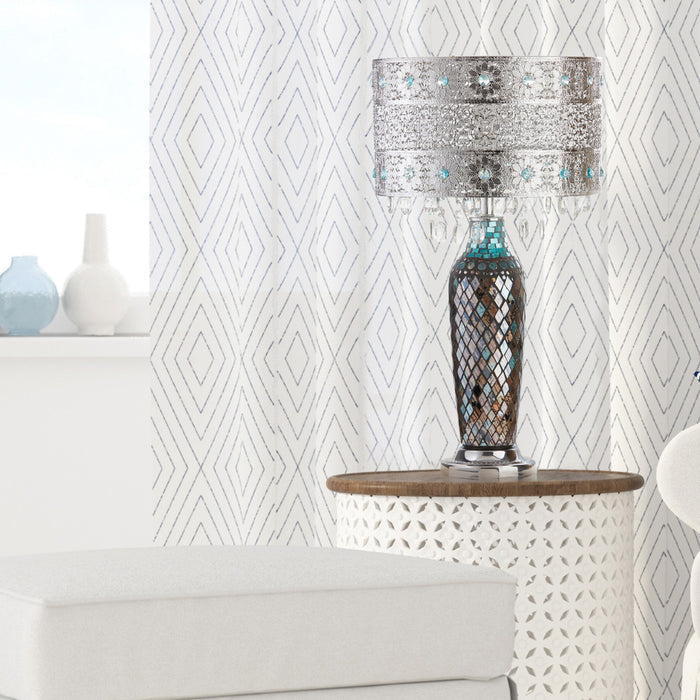 24.25"H Gloria's Crystal Beaded Table Lamp with Mosaic Base on a table against a geometric patterned drapes.