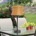 25.25"H Outdoor and Indoor Basket Weave Table Lamp on a glass patio table with flowers and chairs in the background