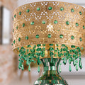 25"H Jeweled Gold Metal and Mosaic Base Table Lamp with Cascading Green Crystals against a blurred out living room scene