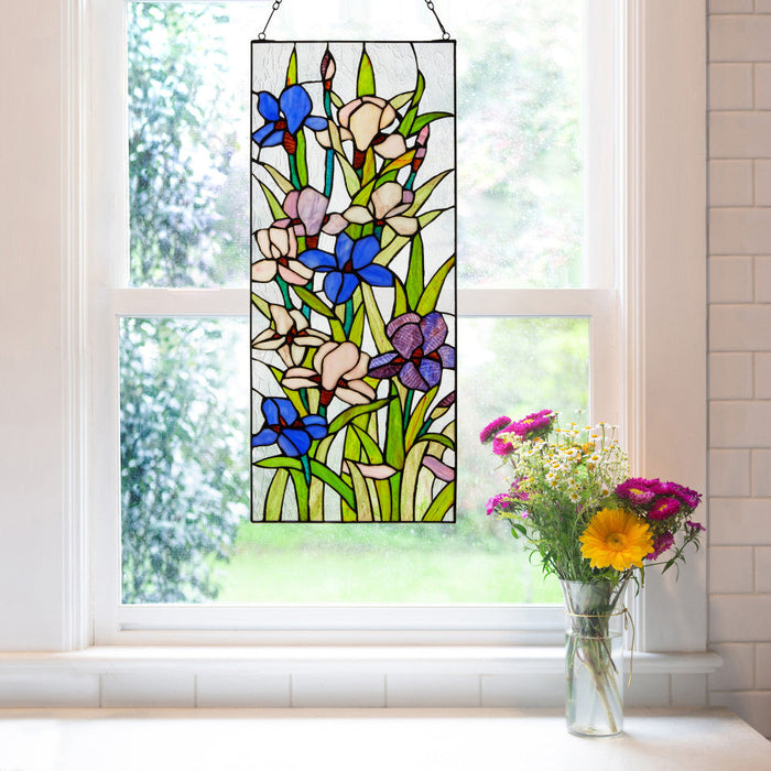 28" H Floral Purple Iris Stained Glass Window Panel hanging on a window, with a vase of flowers on a windowsill.