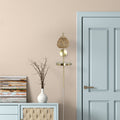 32.75"H Candlestick Wall Sconce with Tan Rattan Shade next to a light blue door and wooden cabinet.