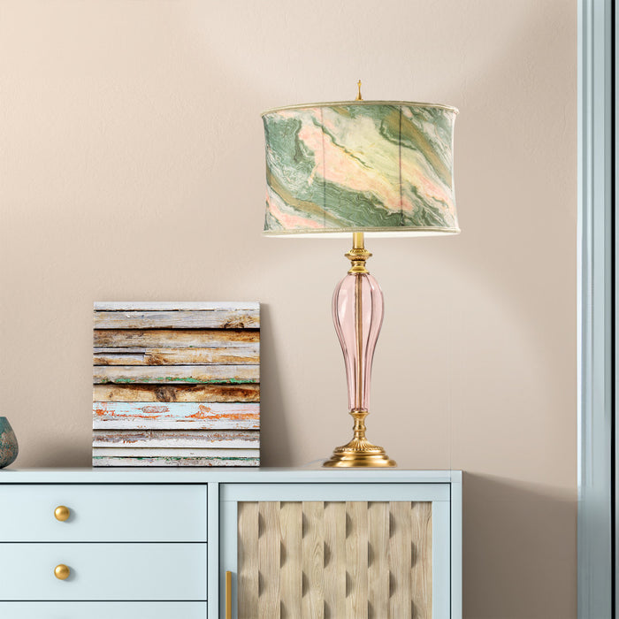 33" H Romance Pink/Green Drum Shade Geometric Glass Table Lamp on a light blue cabinet against a beige wall.