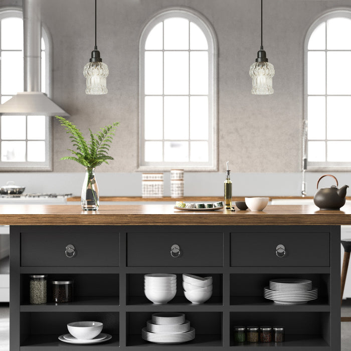 4.5" W 1-Light Luna Glass and Metal Pendant in a modern kitchen with a large island featuring wooden countertop and black cabinets.