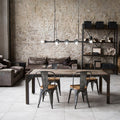 48" L 8-Light Degas Black Metal Industrial Chandelier in a modern dining area with a brick wall background