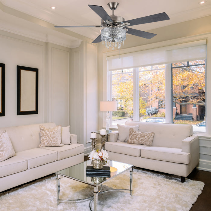 52"W LED Roxsie 5-Blade Crystal LED Chandelier Ceiling Fan in a modern living room with beige sofas, a glass coffee table, and large windows.