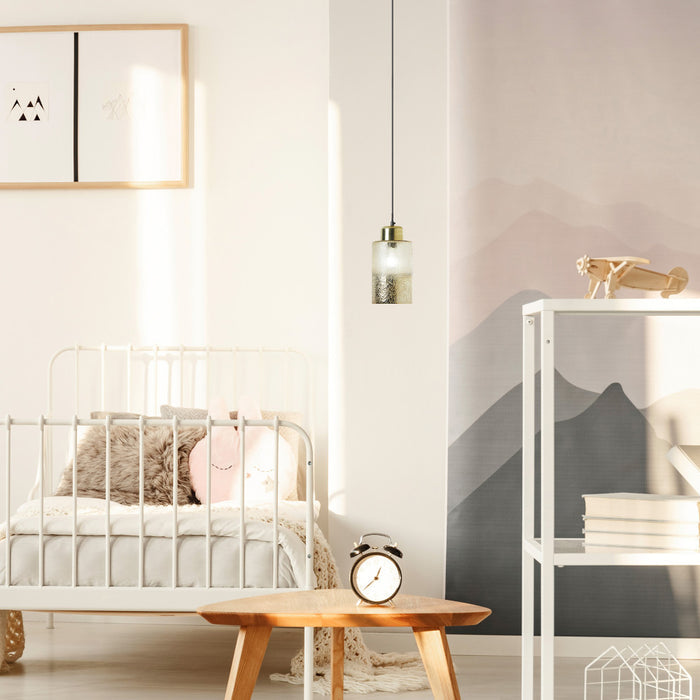 6" Callie Textured Metallic Gold and Clear Ombre Glass Cylinder-Shaped Pendant Lamp in a modern bedroom with a bed, table, and shelves.