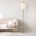 63"H Polished Metal Floor Lamp With Cream Fringe Shade next to a beige sofa in a minimalistic living room.