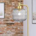 63"H Rowan Globe Shade Floor Lamp against a brick wall.
