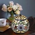 6.5"H Stained Glass Teapot Accent Lamp on a table with flowers and a teacup in the background.