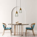 8.25" W Taylor Industrial Emerald Green and Gold Cone-Like Shade Pendant in a dining table with two chairs in a modern interior setting.