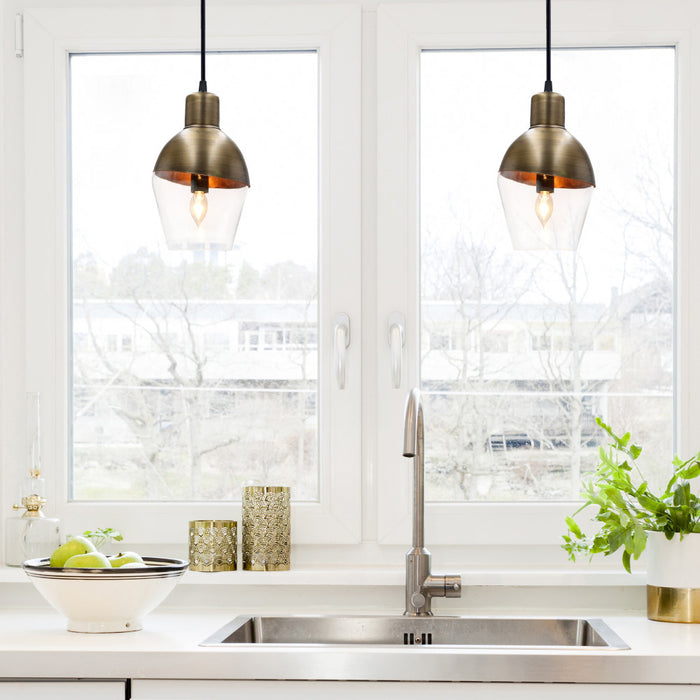 9.25" Asymmetrical Golden Glass 1-Light Pendant in a modern kitchen with sink and decorative items.