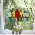9.5"H Birds in Love Stained Glass Window Panel hanging on a window with a view of trees.