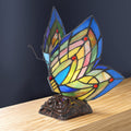 9.5"H Stained Glass Butterfly Wings Accent Lamp on a wooden surface with a dark background