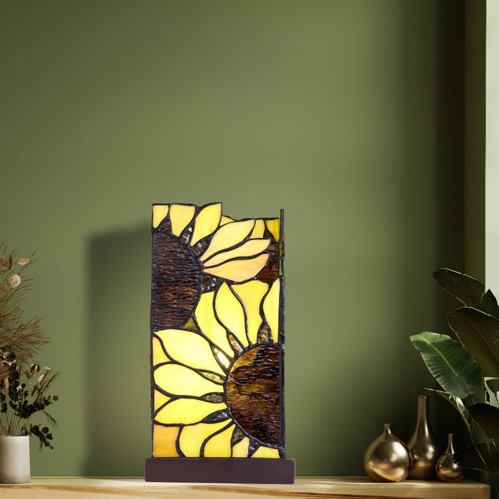 9.75" H Sunflower Stained Glass Hurricane Uplight Accent Lamp on a wooden surface against a green wall.