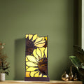 9.75" H Sunflower Stained Glass Hurricane Uplight Accent Lamp on a wooden surface against a green wall.