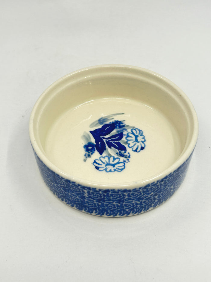 Angled top-down view into the open base of a Ceramika Artystyczna Polish pottery trinket box, revealing a hidden hand-painted blue-and-white floral bouquet on the interior.