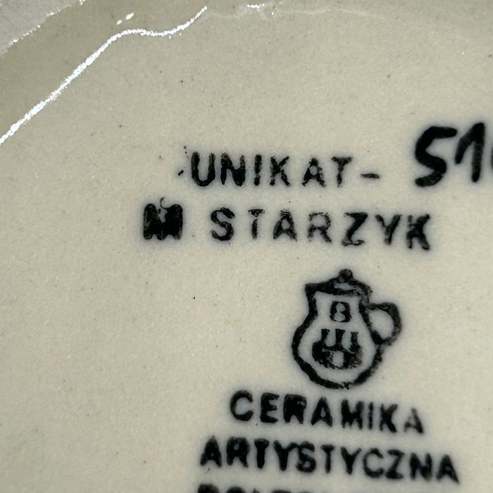 Extreme close-up of the bottom stamps on a Ceramika Artystyczna Polish pottery mug showing the Unikat designation, M. Starzyk artist name, Ceramika Artystyczna's logo, and Ceramika Artystyczna text.