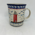 Front view of a large 16oz Ceramika Artystyczna Polish pottery B13 mug in the Unikat U5164 pattern, featuring a red lighthouse, classic straight sides, and an blue rim.