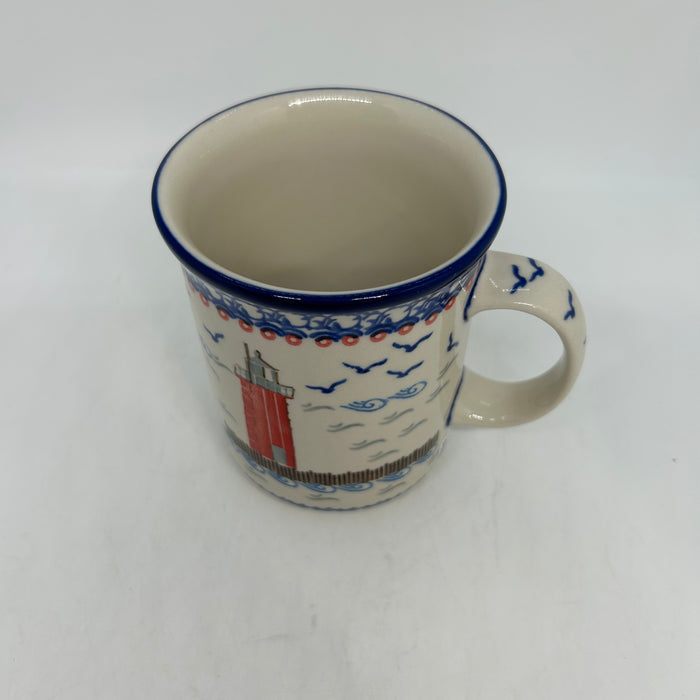 Angled top-down view of a large 16oz Ceramika Artystyczna Polish pottery B13 mug in the Unikat U5164 pattern, showing the lighthouse exterior, straight sides, blue rim, and the interior.