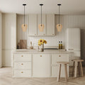 Chanda 9.25"W Glam Gold Bell Pendant Light in a modern kitchen with light wood cabinets, white marble countertop, and wooden stools.