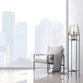 Leticia Black Metal and Champagne Gold Glass Bowl 61-Inch Floor Lamp next to a modern chair with a pillow in a room with large windows showing cityscape.