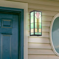 Green Stained Glass and Black Metal Rectangular 1-Light Outdoor Wall Sconce on a house exterior with a blue door and round window.