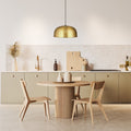 Sibyl 17.75"W Star-Shaped Cutout Gold Pendant Light hanging in a dining area with a round wooden table and chairs and kitchen cabinets.