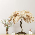 The 30" H Sammy Bronze Tropical Palm Tree Table Lamp on a wooden surface against a light gray wall.